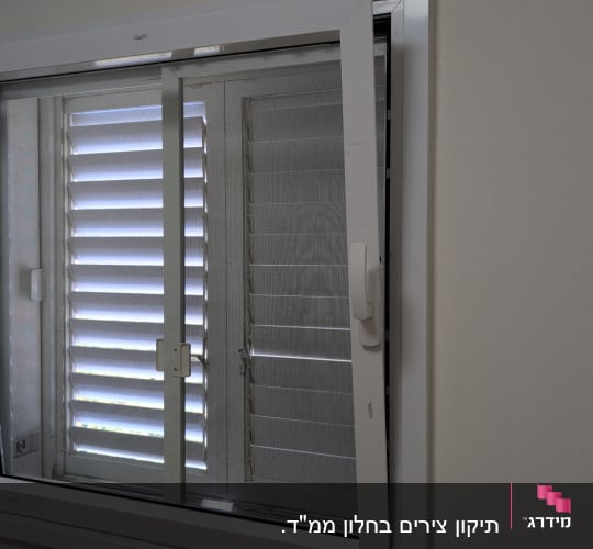 חלון עם תריסים פתוחים למחצה בתוך חדר